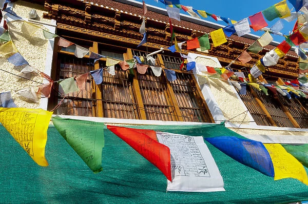 India, Jammu & Kashmir, Ladakh, prayer flags blowing in front of a traditional Ladakh
