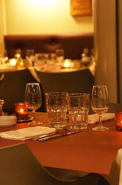 Interior of The restaurant Brunel at night. Tables with glasses, knives, ofrks, glasses
