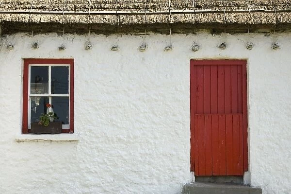 Ireland, Gleann Cholm Chille. Details of a thatched-roof cottage with a red door