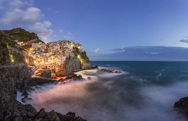 Italy, Cinque Terre, Manarola. Hilltop town and stormy ocean at sunset. Credit as