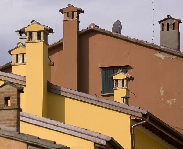 Italy, Dozza. Old and new roof lines with stone chimneys and a satellite dish