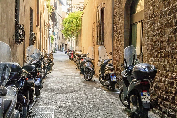 Italy, Florence. Deteriorating stone wall and colorful mopeds and motor bikes
