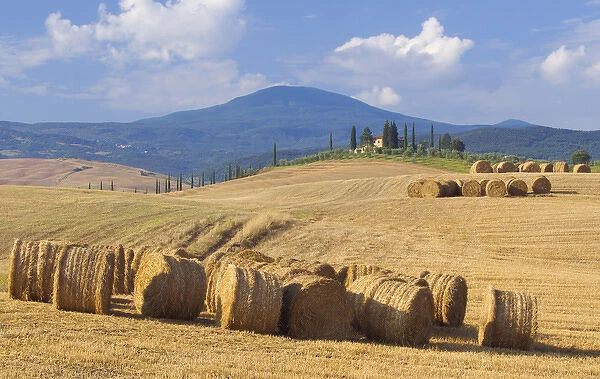 Italy, San Quirico d Orcia. Bales of hay and farm house
