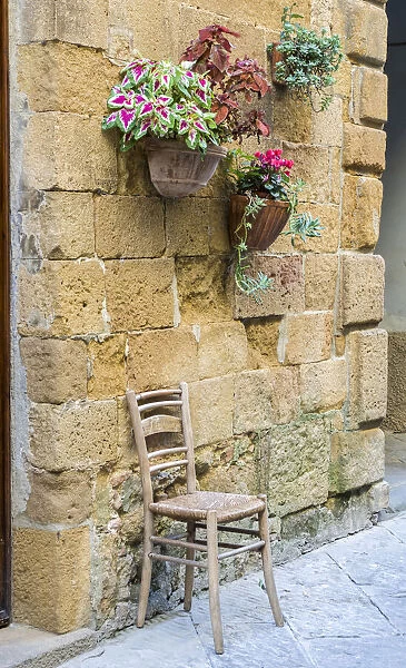 Italy, Tuscany. Chair and flower pots outside the entrance to a shop in a village in