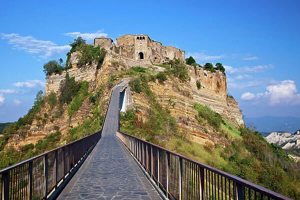 Italy, Tuscany. Evening view of Civita di Bagnoregio and the long bridge leading to town