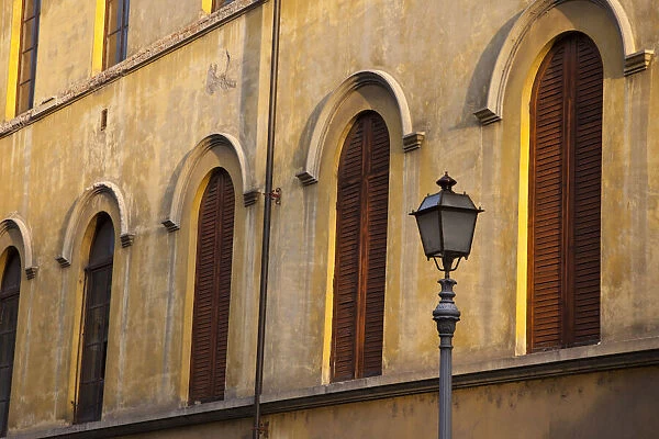 Italy, Tuscany, Lucca. Street lamppost and arched windows with wooden shutters