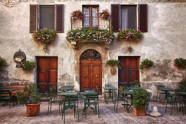 Italy, Tuscany, Pienza. Tables and chairs set up outside for outdoor dining in the town of Pienza