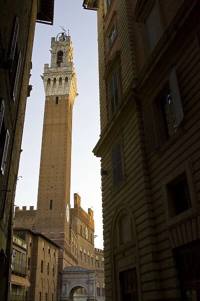 Italy, Tuscany, Sienna. Looking down a narrow street at the Torre del Mangia framed by buildings