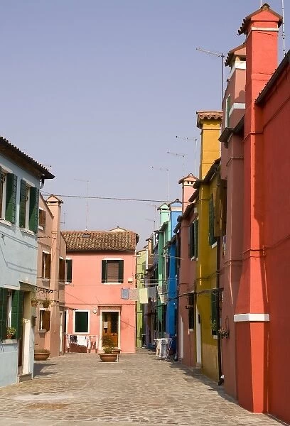 Italy, Venice, Burano. A typical street lined with colorful houses and laundry on the line