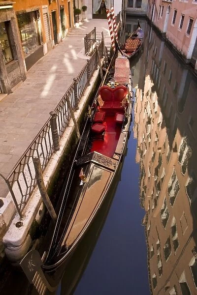 Italy, Venice. Gondola parked in a canal with building reflection