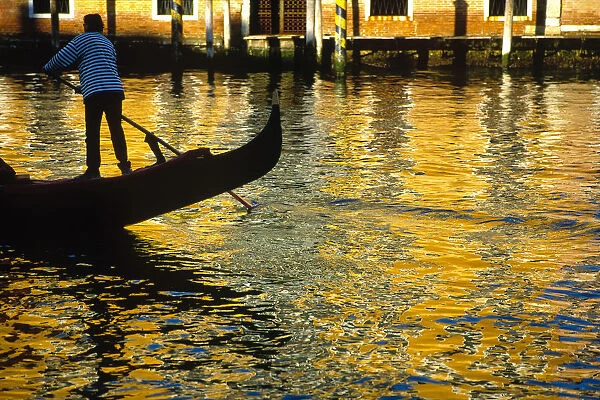 Italy, Venice. Gondolier steering gondola at sunset