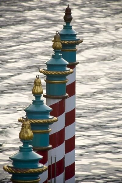 Italy, Venice. A line of gondola parking poles striped in red and white