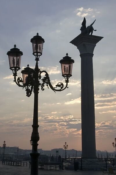 Italy, Venice. Lion of St. Mark atop column and ornate lamp at sunrise