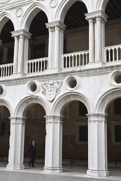 Italy, Venice. Man walks beneath the arches of the interior of Doges Palace