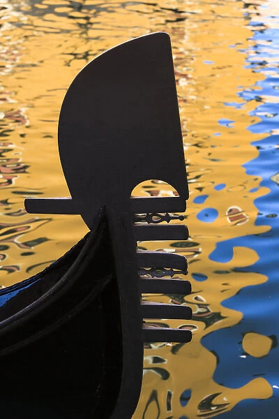 Italy, Venice. A silhouette of a gondola against colorful water reflections