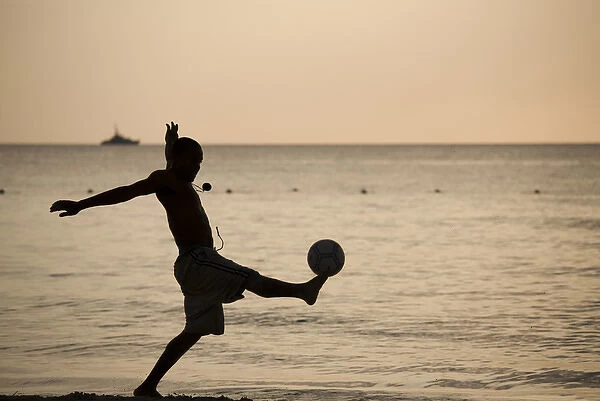 Jamaica, Negril, Silhouette of young men playing soccer along Caribbean Sea