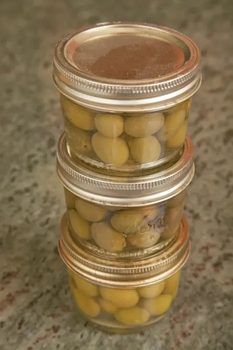 Framed Print : Three jars of home canned olives on a granite countertop in a kitchen