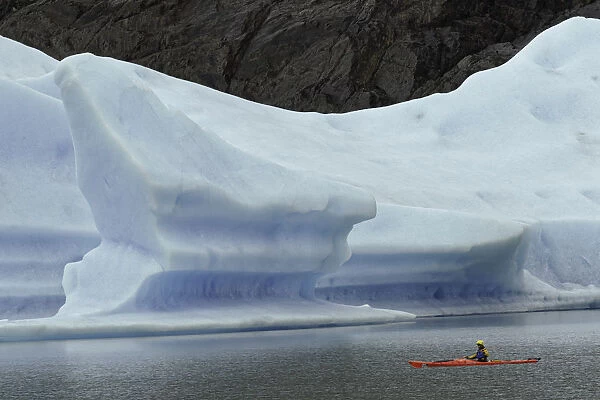 Kayakers exploring Grey Lake amid large iceberg, Torres del Paine National Park
