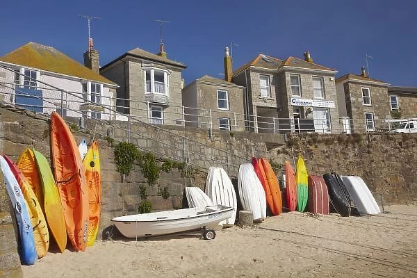 Kayaks and dinghies stacked against seawall at Mousehole, near Penzance, Cornwall