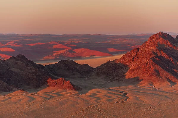 Light illuminates the Naukluft Mountains and Namib Desert at sunrise. Namib Naukluft Park, Namibia
