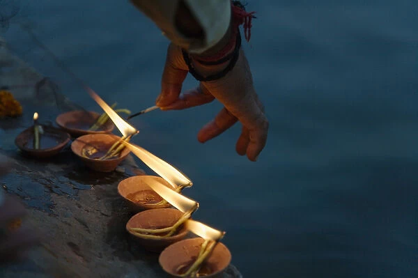 Lighting flower lamps by the Ganges River, Varanasi, India