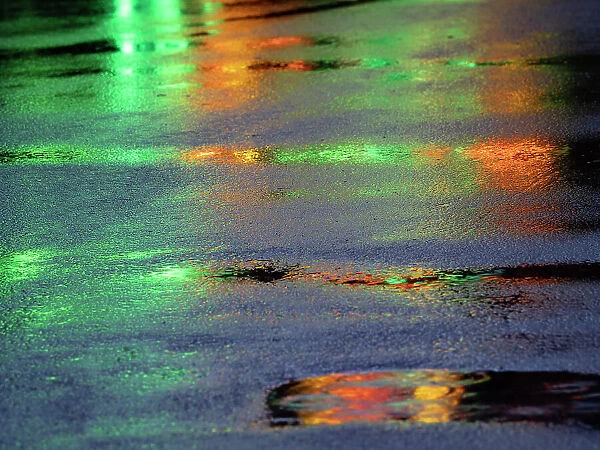 Lights reflected in puddles on asphalt path