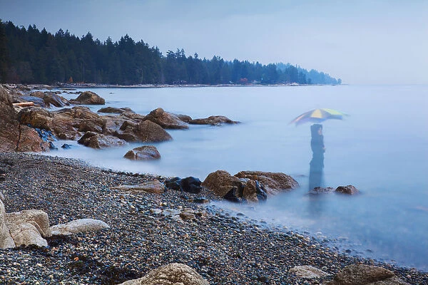 Long exposure of a ghostly image of woman in the sea with umbrella Sechelt, British Columbia