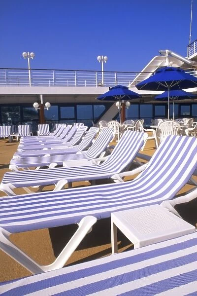 Lounge chairs, tables, umbrellas on the deck of a cruise ship