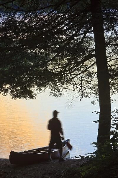 A man next to his canoe at Zack Woods Pond, Hyde Park, Vermont. Early morning