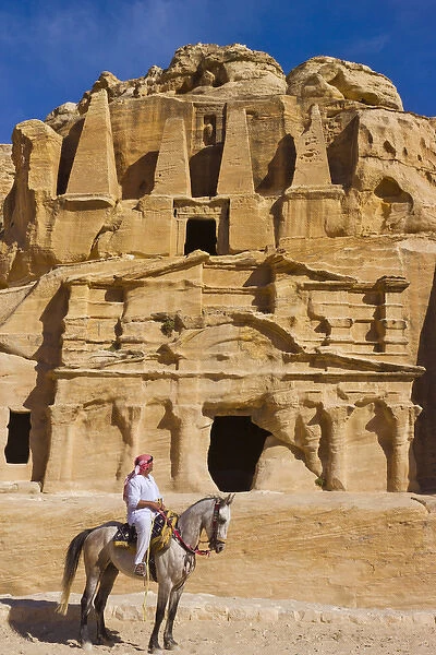 Man riding on horse with the Tomb of Obelisks, Petra, Jordan (UNESCO World Heritage site)