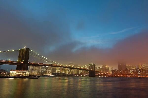 Manhattan skyline and the Brooklyn bridge in the mist at dusk