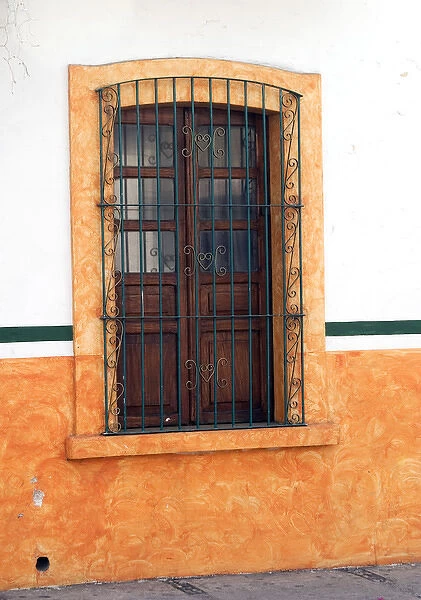 Mexico, Cabo San Lucas. Detail of colorful wooden window with decorative wrought iron bars