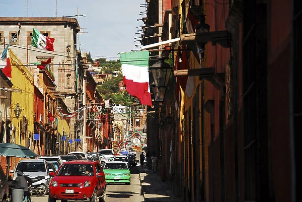Mexico, San Miguel de Allende, flag flattering on buildings, car moving on street