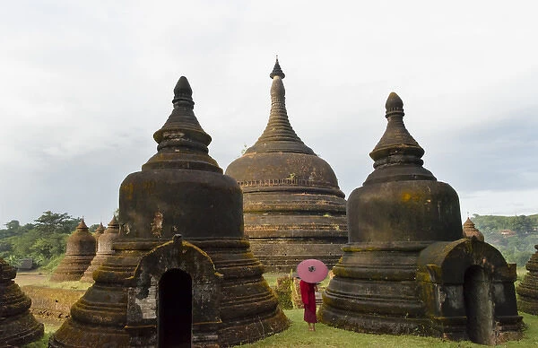 Monk holding red umbrella with Andaw-thein Temple, Mrauk-U, Rakhine State, Myanmar