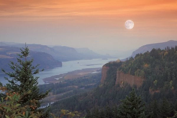 The moon hangs in the sky above the Vista House, high on Crown Point as sunset falls