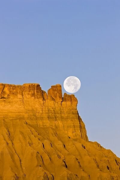 A full moon sets over Factory Butte at sunrise in the desert of southwestern Utah