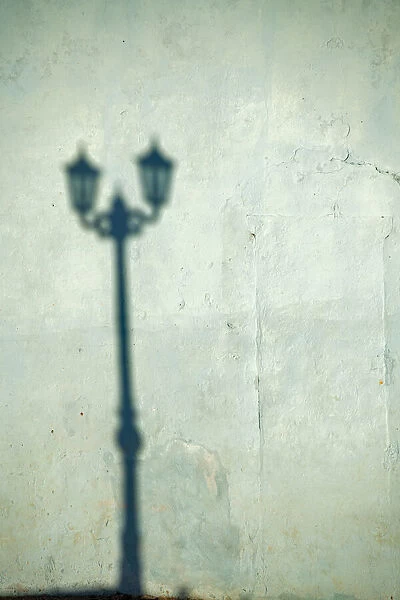 Morning shadow of a lamppost on light blue-green house wall in Trinidad, Cuba