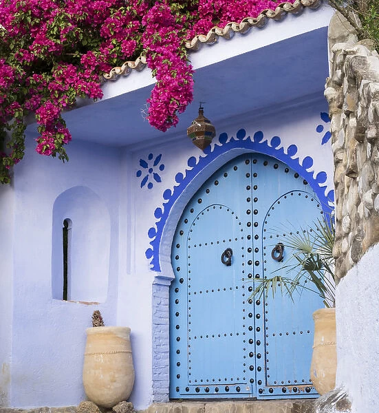 Morocco, Chefchaouen. Bougainvillea blossoms frame an ornate blue door