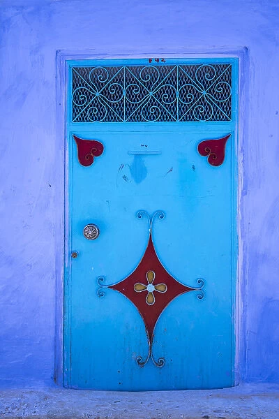 Morocco, Chefchaouen. A traditional metal painted door with red heart-like motifs