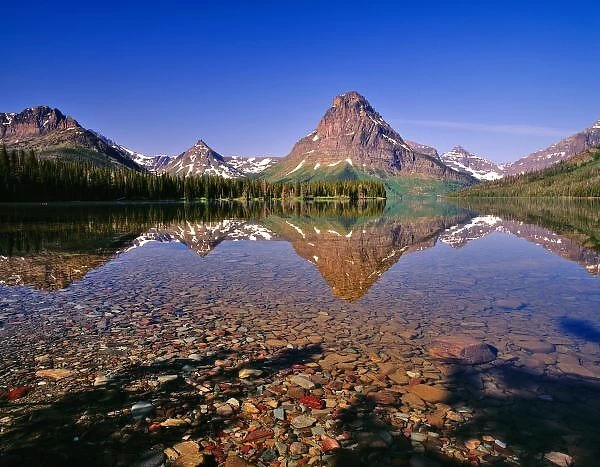 Mountains reflect into calm Two Medicine Lake in Glacier National Park in Montana