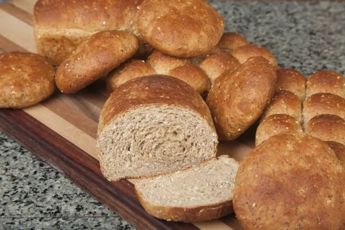 Framed Print : Multigrain rolls, buns and loaf with a slice cut off, on bread board Framed Print : Multigrain rolls, buns and loaf with a slice cut off, on bread board