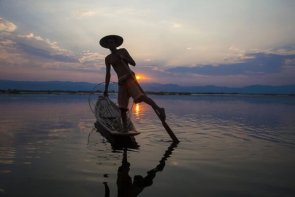 Myanmar, Inle Lake. Fisherman rowing at sunset