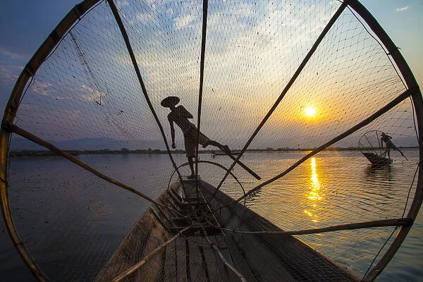 Myanmar, Inle Lake. Fishermen rowing at sunset