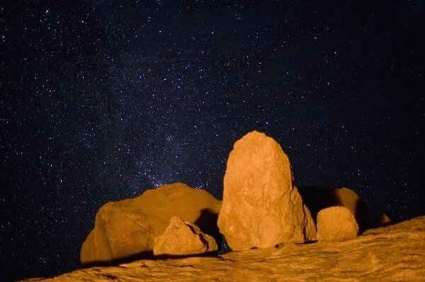 Namibia, Usakos, Orange light from campfire illuminates granite boulders near Spitzkoppe