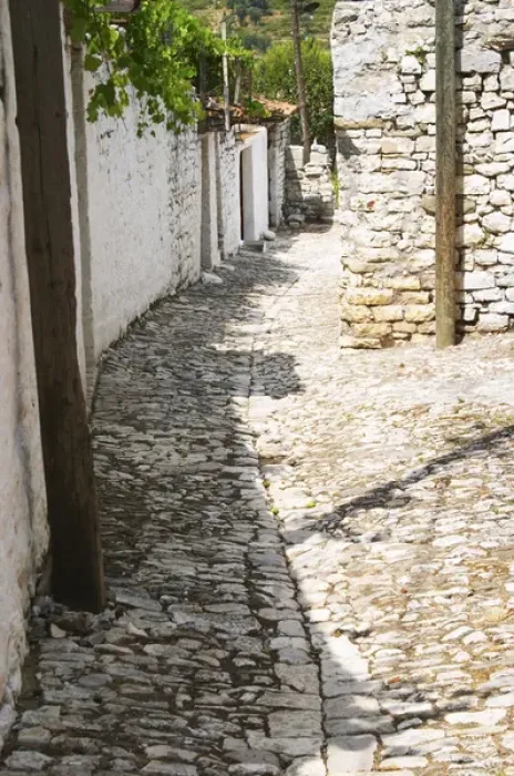 Framed Print : A narrow cobble stone street lined with white stone houses. Berat upper citadel old walled city