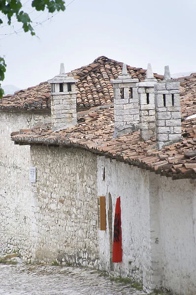 Narrow cobble stone street with traditional ottoman white stone houses. An Albanian