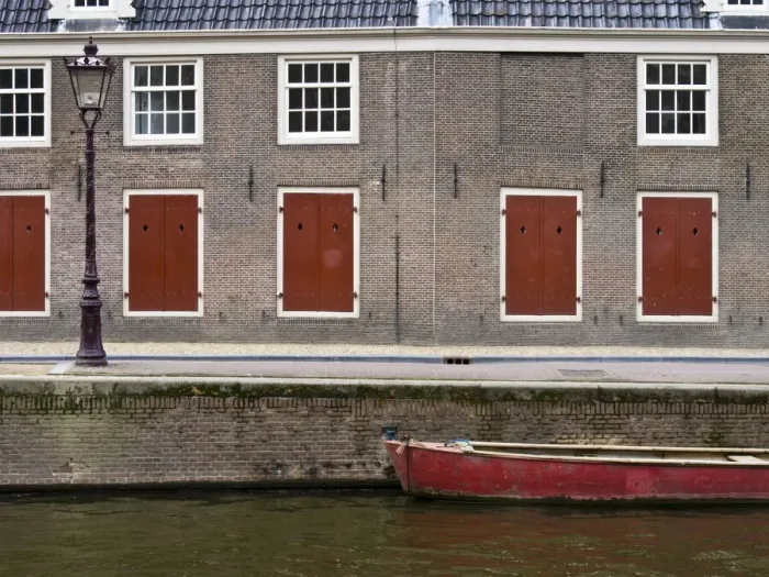 Framed Print : Netherlands, Amsterdam. Colorful red doors along the canal with a red boat