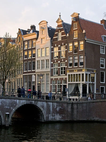 Netherlands, Amsterdam. Traditional houses along the canals and bridge crossing