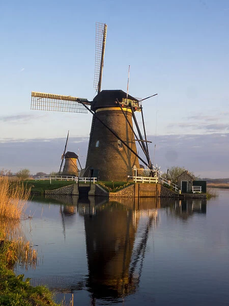 Netherlands, Kinderdijk. Windmill along the canal with morning light