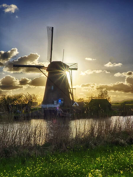 Netherlands, Kinderdijk. Windmill along the canal at sunset